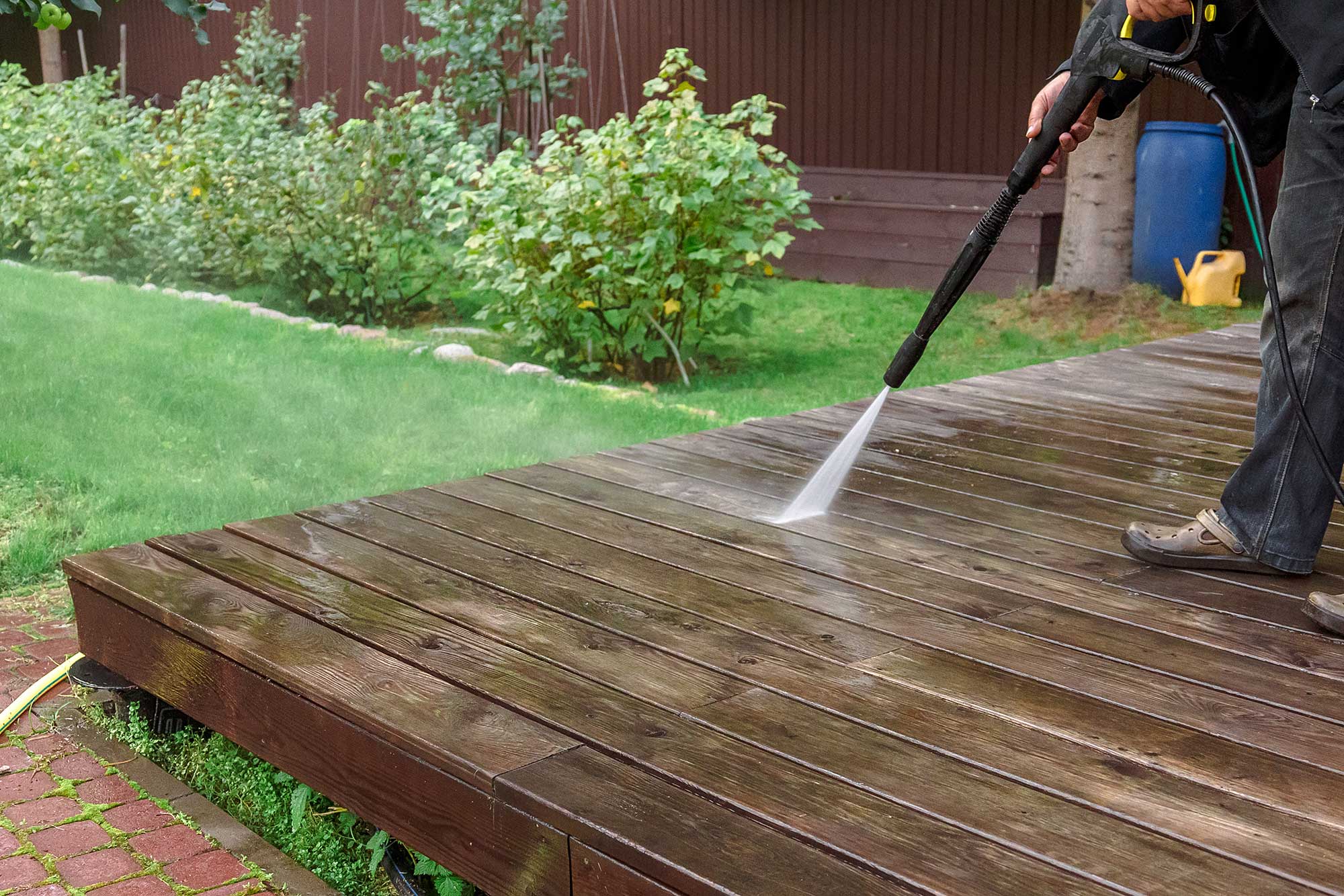 Pressure washing a wooden deck to restore color and remove dirt.